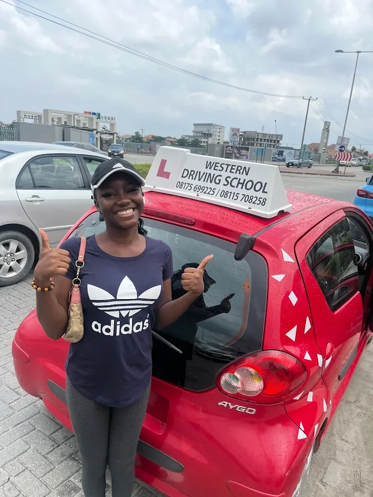 Happy WDS student giving a thumbs up beside a training car